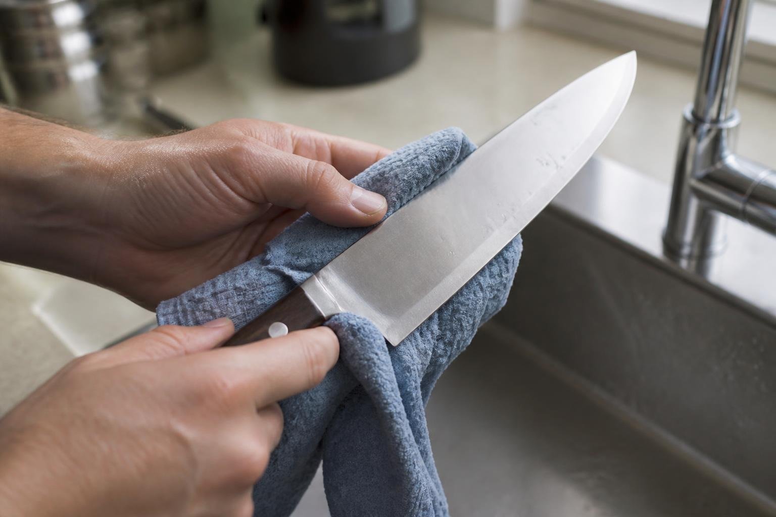 Un couteau de cuisine étant nettoyé et essuyé délicatement
